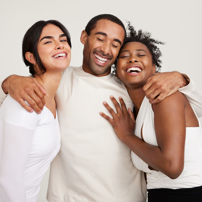 Un grupo de dos mujeres y un hombre riendo y abraz&aacute;ndose 