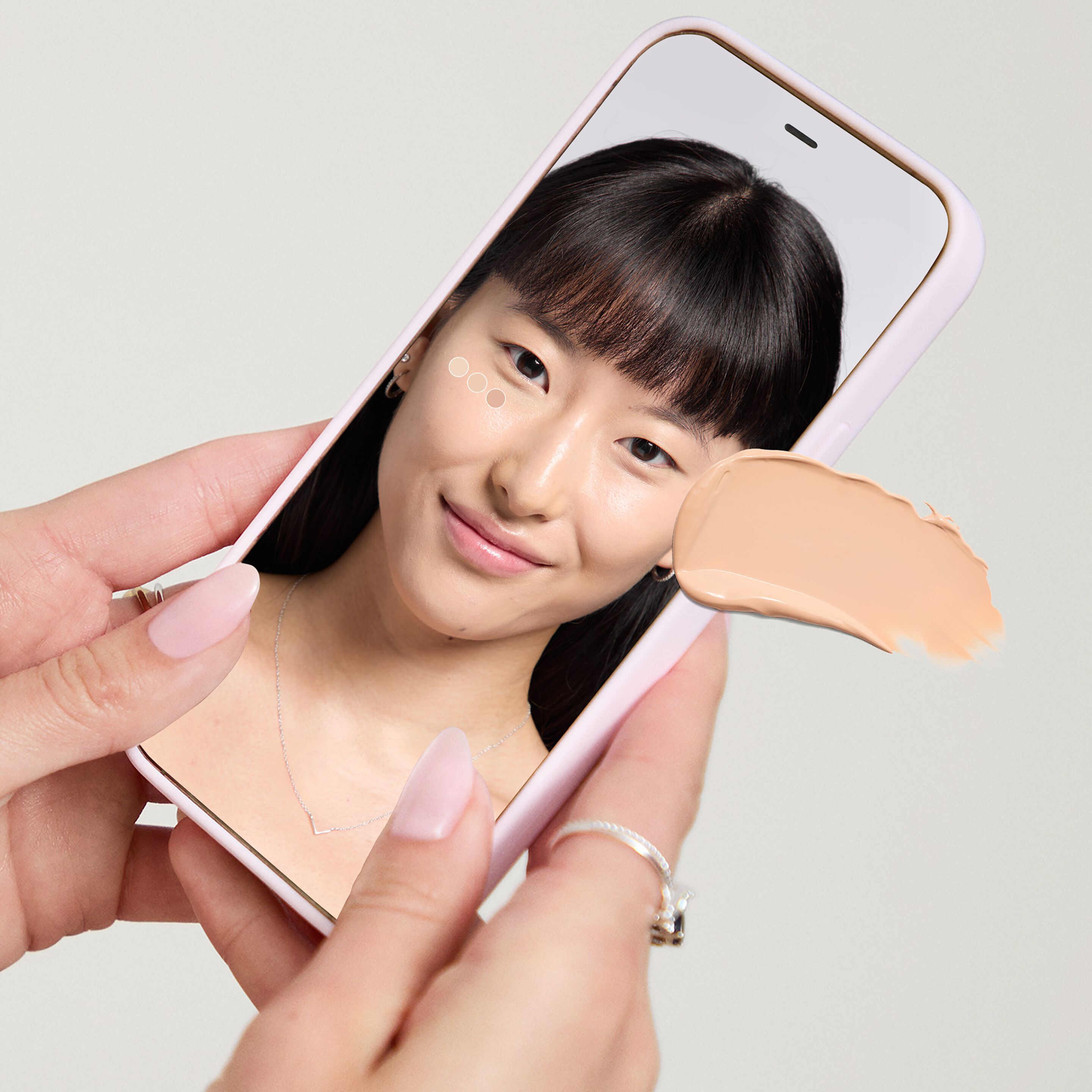 Manos de tono de piel claro sosteniendo un celular que muestra la herramienta Mary Kay Tu Base Ideal.