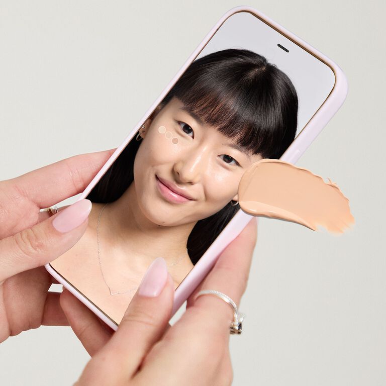 Manos sosteniendo un dispositivo m&oacute;vil que muestra la herramienta Mary Kay Tu Base Ideal.