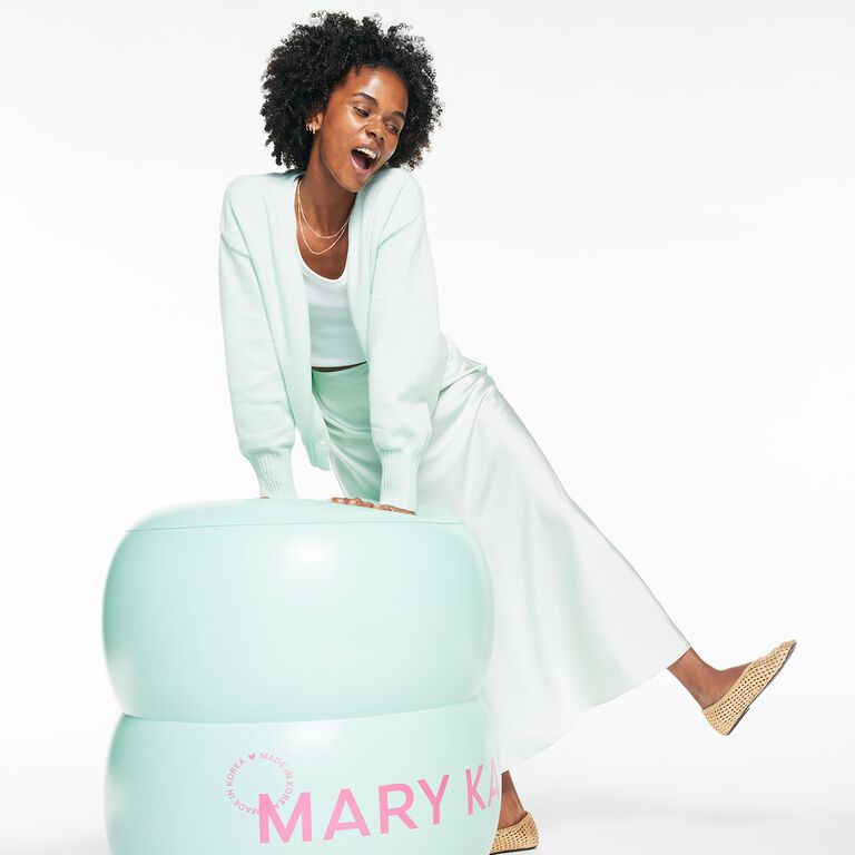 Mujer recarg&aacute;ndose sobre un inflable de B&aacute;lsamo Limpiador Facial Mary Kay&reg; de Edici&oacute;n Especial