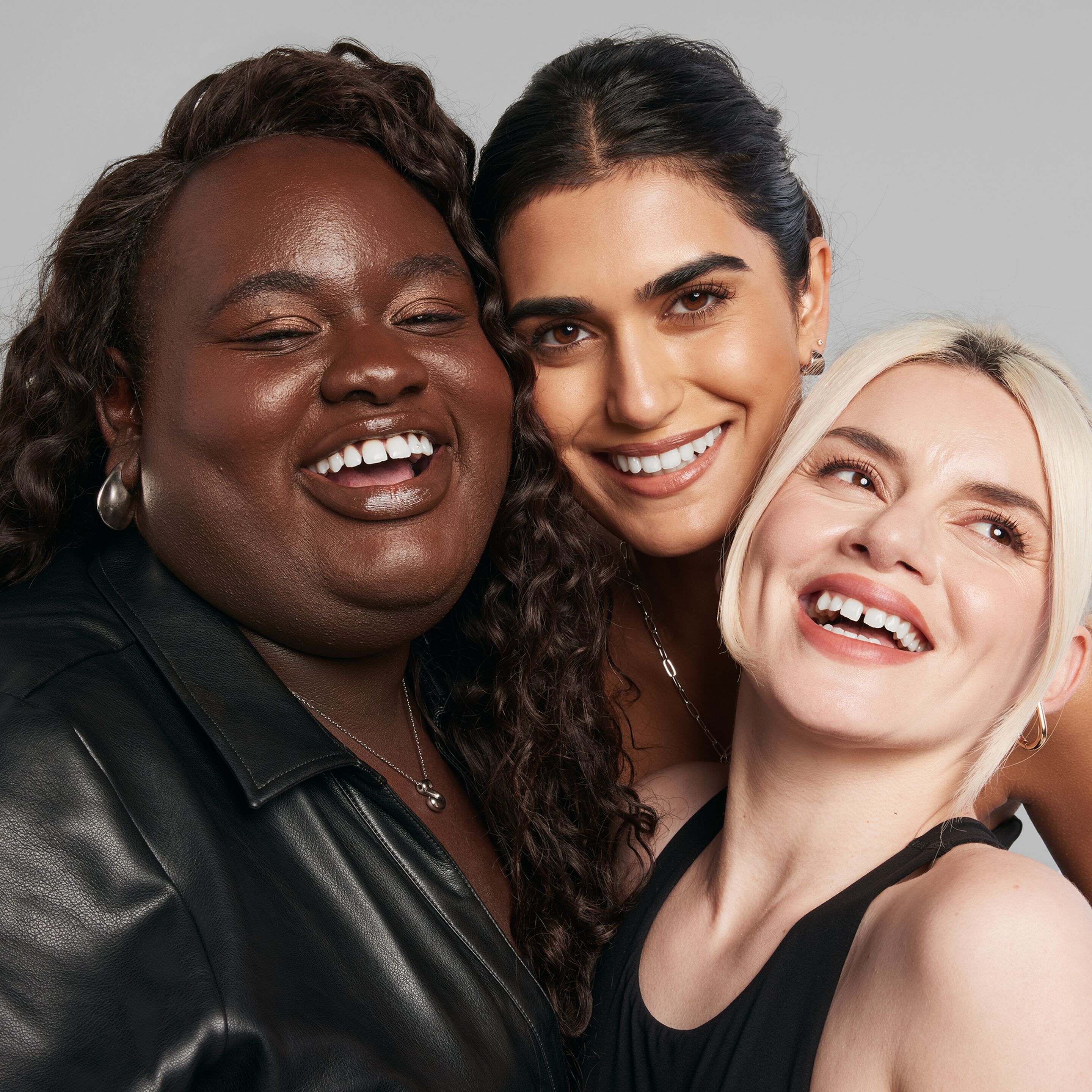 Tres mujeres de pie juntas con diferentes tonos de piel.