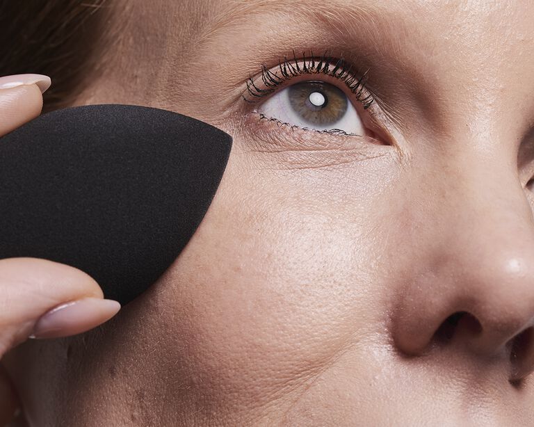 Acercamiento al rostro de una mujer sosteniendo la Esponja para Maquillaje Mary Kay&reg; en su mejilla.
