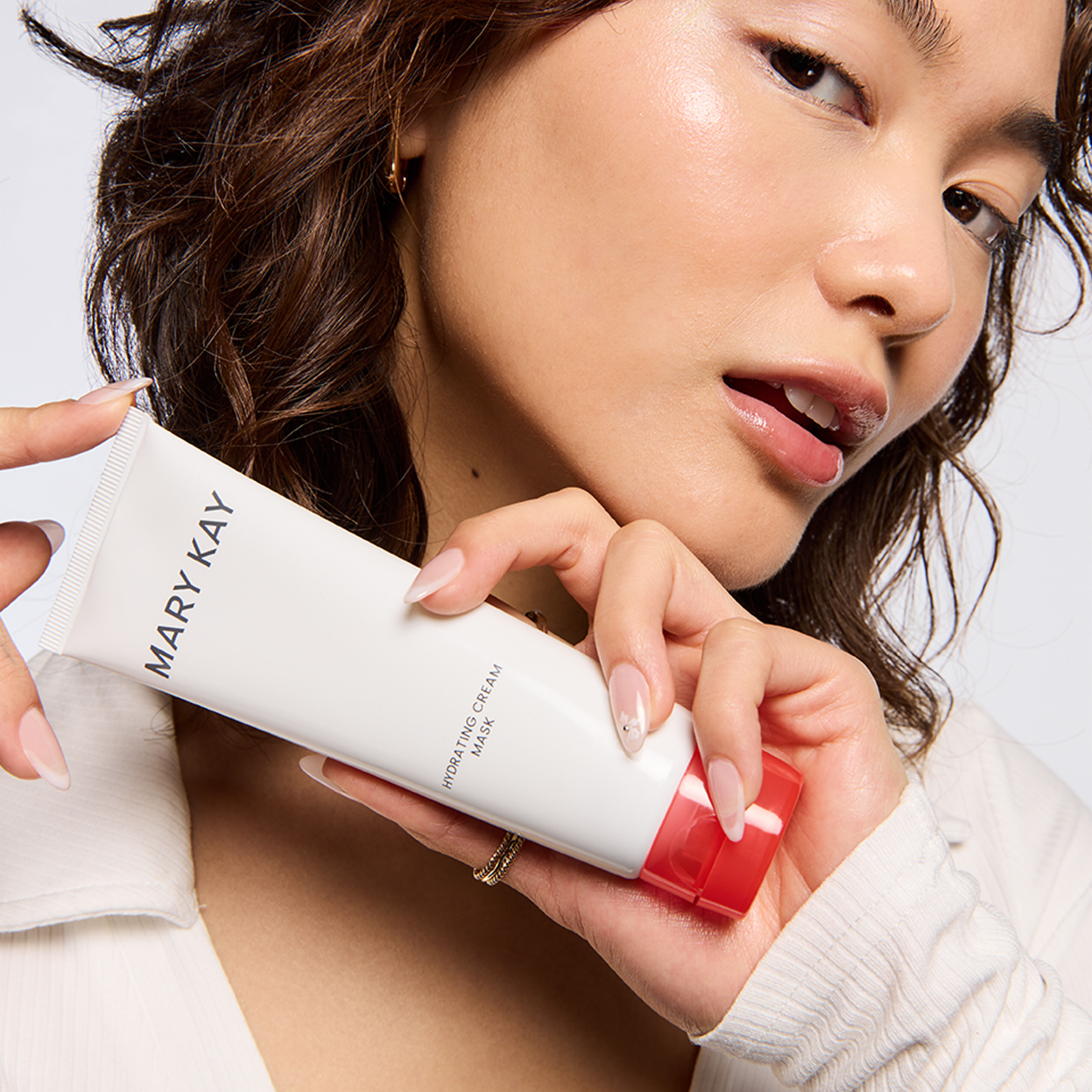 Mujer sosteniendo Mascarilla Hidratante en Crema Mary Kay&reg; cerca de su rostro