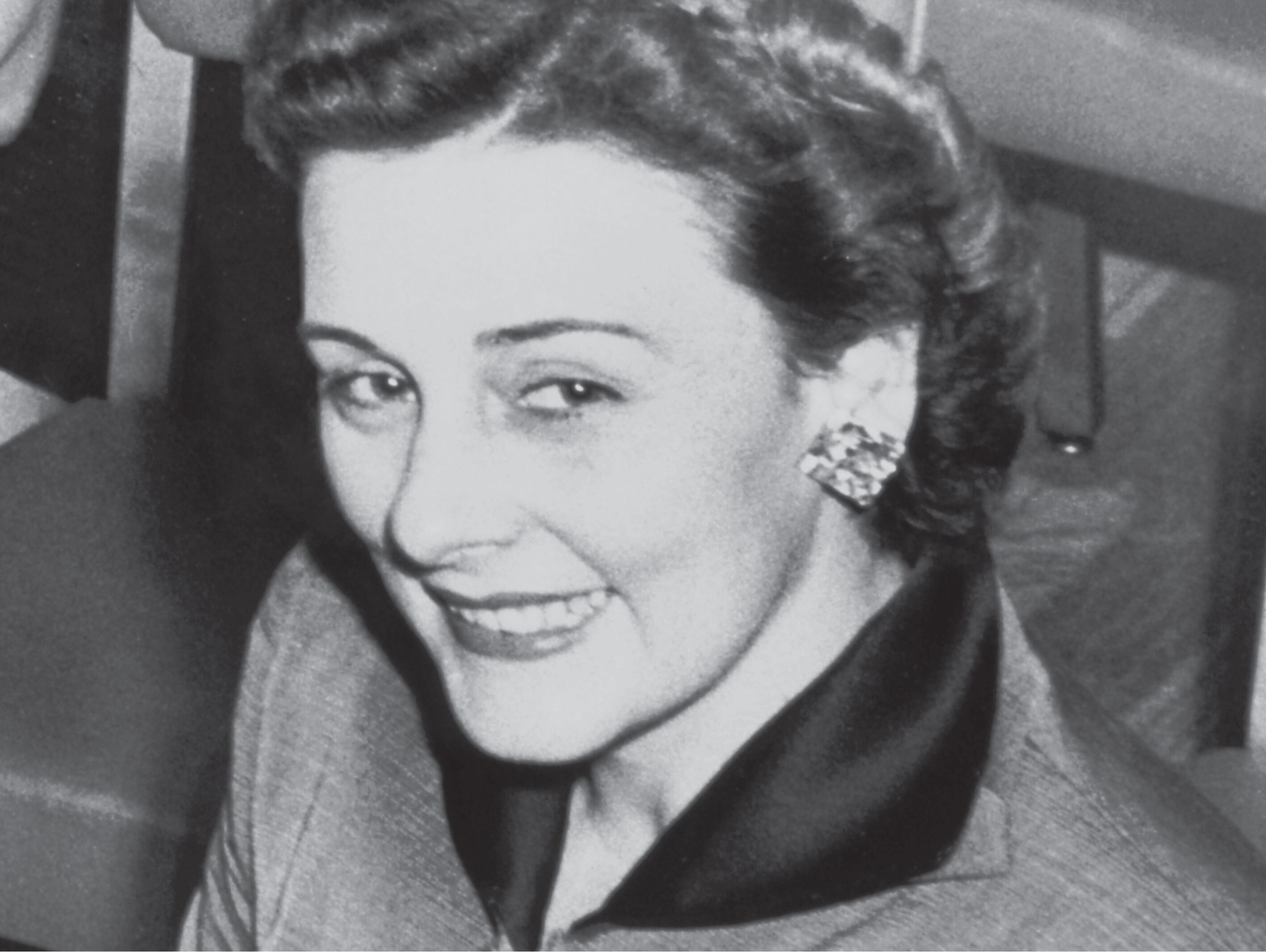 Fotograf&iacute;a vintage de la fundadora de Mary Kay Ash usando un traje elegante y aretes llamativos.