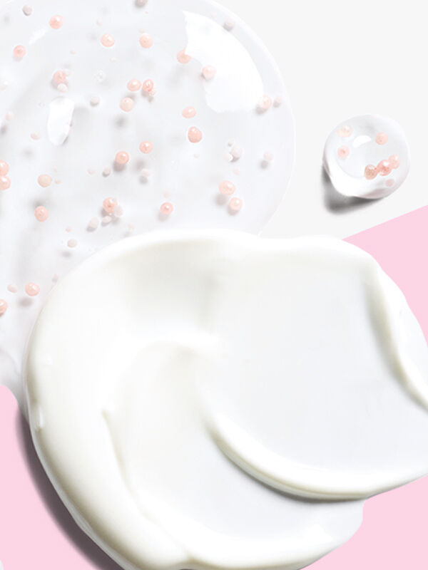 Una peque&ntilde;a cantidad de la crema de d&iacute;a del &ldquo;Set Milagroso&rdquo; de Mary Kay (Loci&oacute;n Facial Protectora de D&iacute;a con FPS 30 TimeWise&reg;) y una peque&ntilde;a cantidad del suero nocturno (Gel Facial de Recuperaci&oacute;n Nocturna TimeWise&reg;), sobre un fondo rosa y blanco.