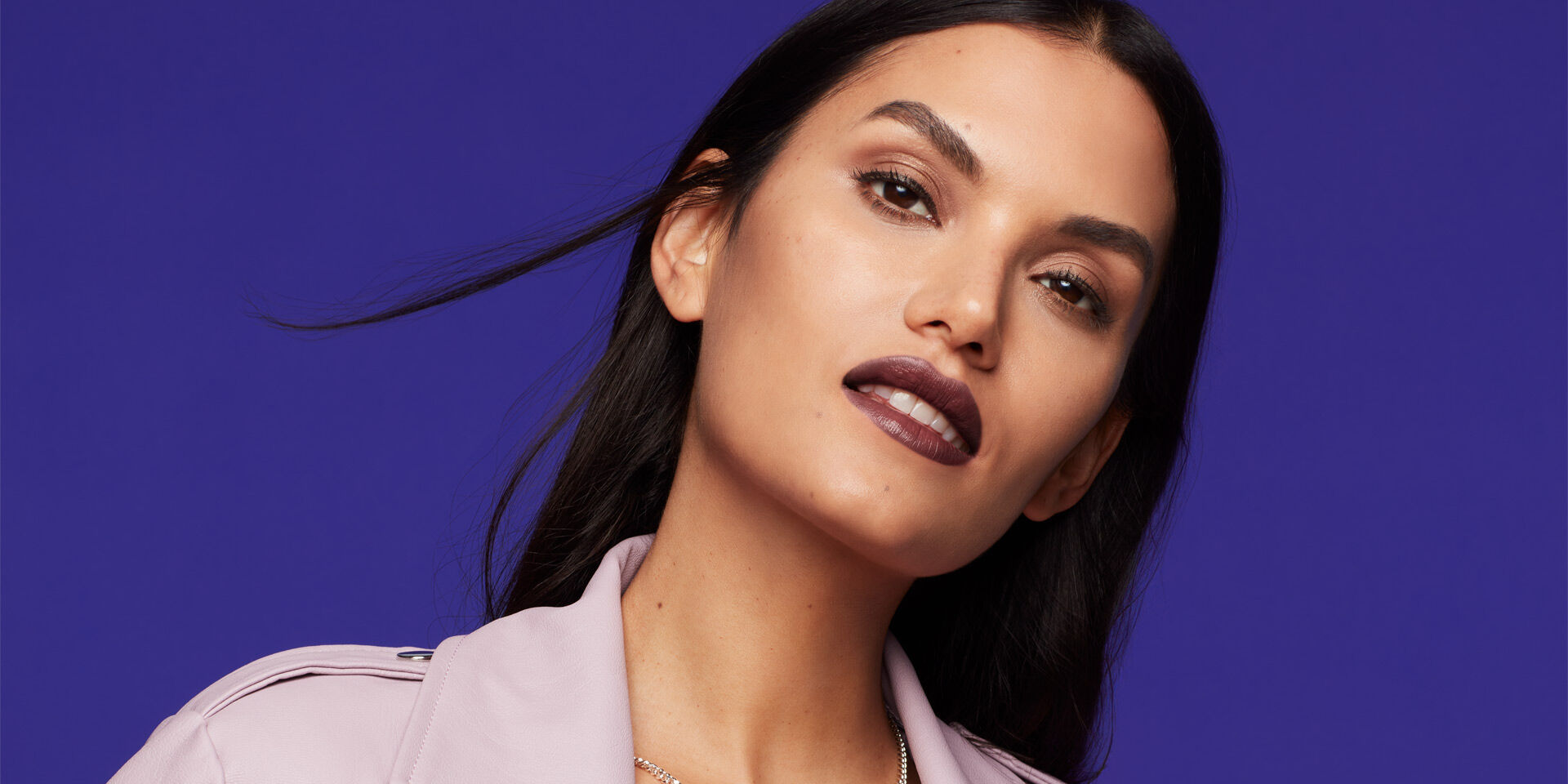 Mujer usando L&aacute;piz Labial Hidratante Mary Kay&reg; Supreme en tono profundo viendo a la c&aacute;mara