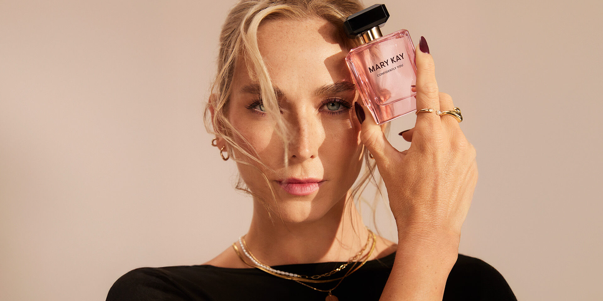 Mujer sosteniendo un frasco de Mary Kay Confidently You Eau de Parfum cerca de su rostro.