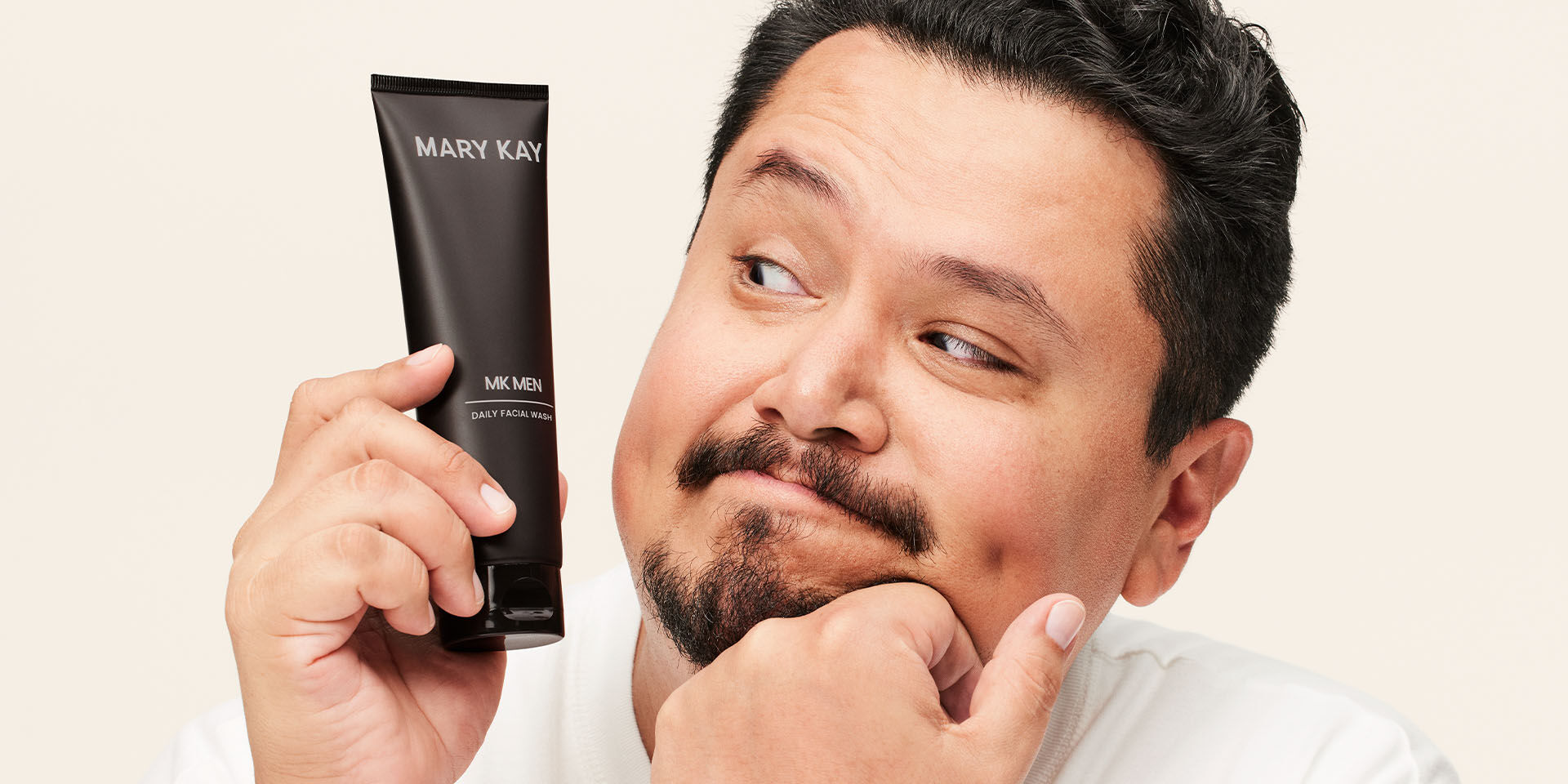 Modelo masculino sosteniendo el Gel Limpiador Facial MK Men&reg; cerca de su rostro.