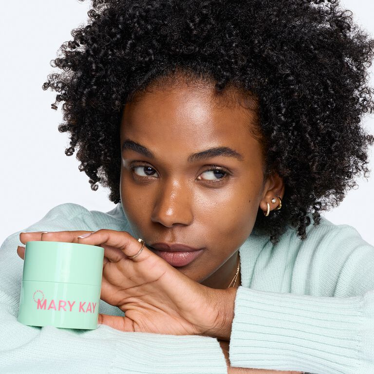 Mujer sosteniendo un frasco de B&aacute;lsamo Limpiador Facial Mary Kay&reg; de Edici&oacute;n Especial cerca de su rostro