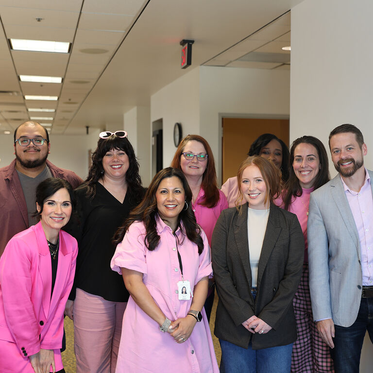 Colaboradores Mary Kay reunidos, vistiendo de rosa y vestimenta de negocios. 