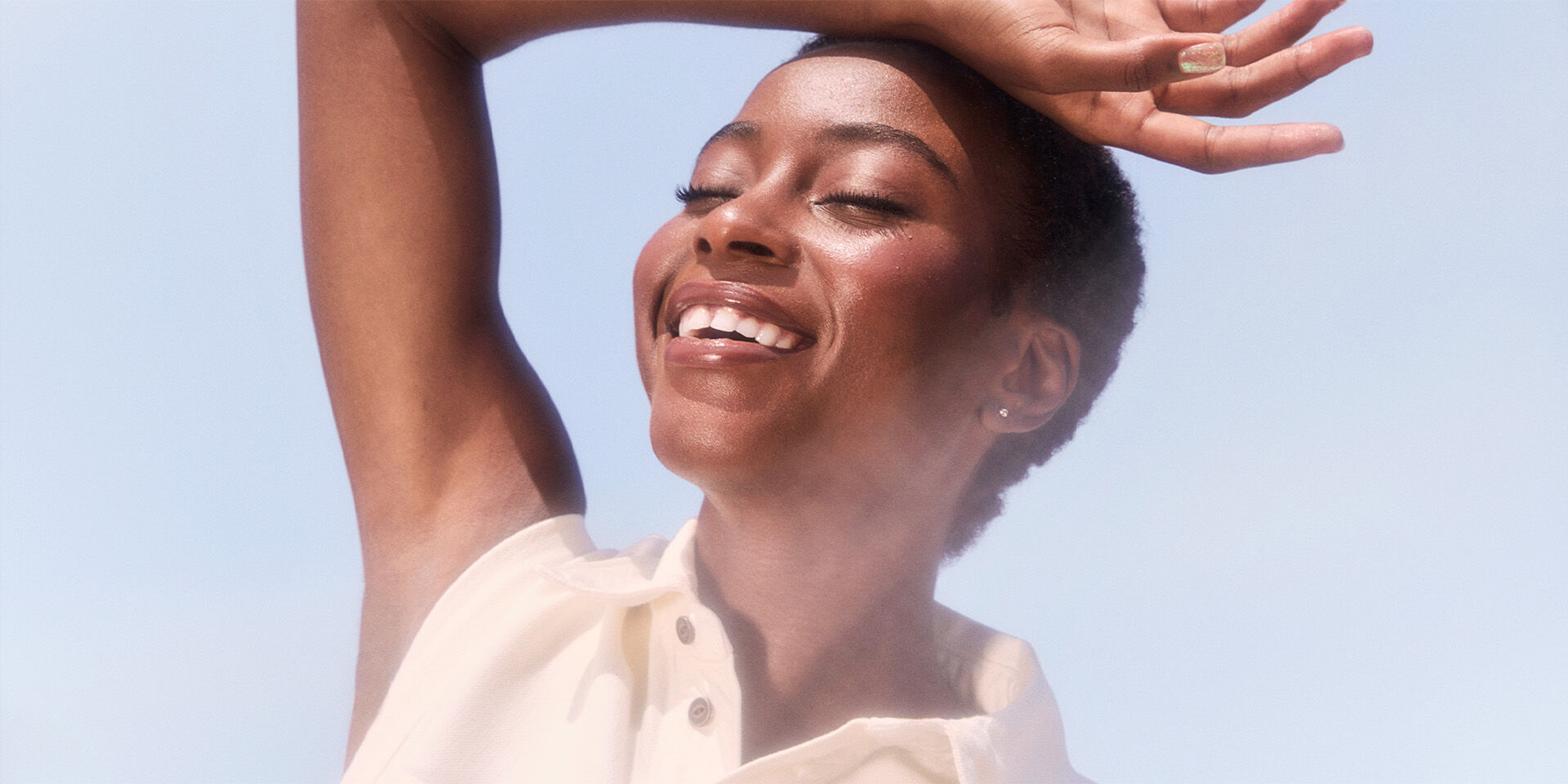 Modelo sonriendo bajo un cielo azul y el sol