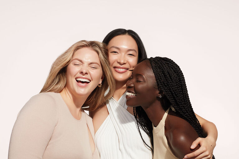Un grupo de tres mujeres sonriendo.