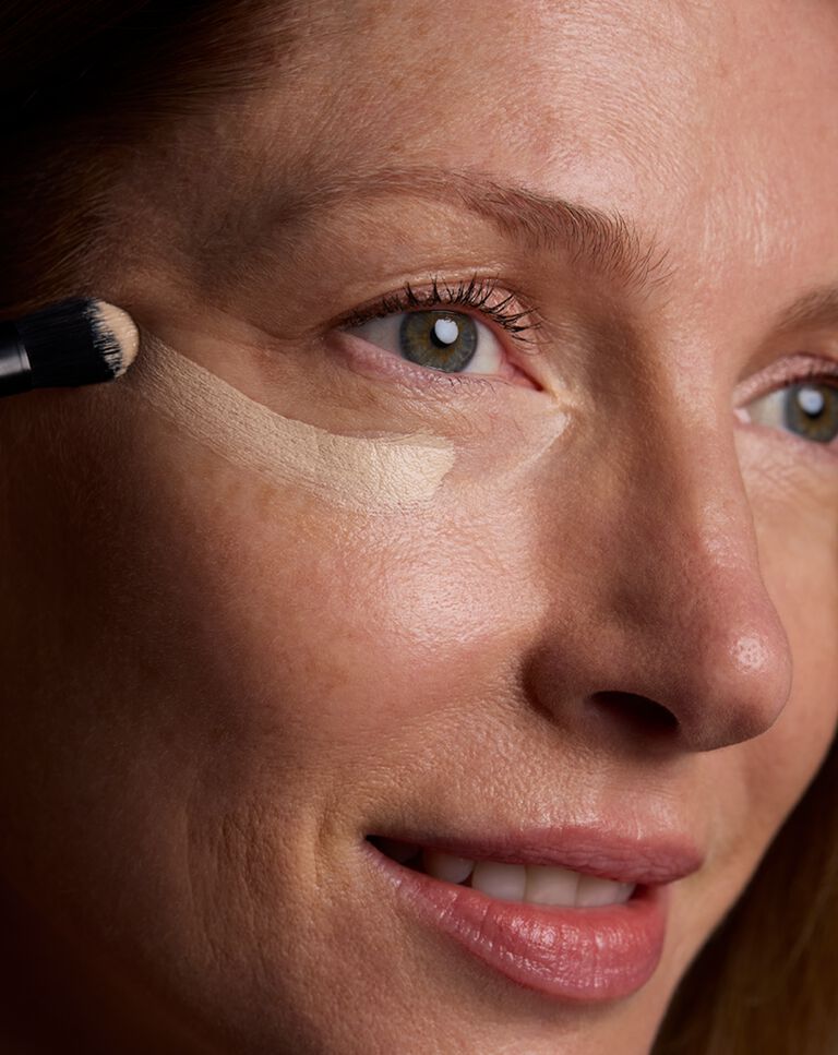 Makeup brush covered in a light shade of concealer 