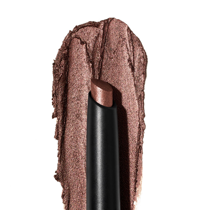 A product rub showing off the Radiant Bronze shade, finish and texture appears on a white surface with the uncapped product in front of it.