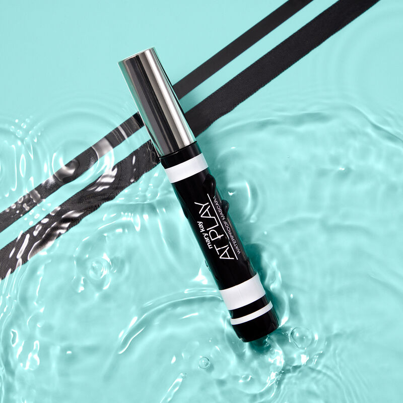 Closed tube of Mary Kay At Play Waterproof Mascara in water with two diagonal black stripes in the background