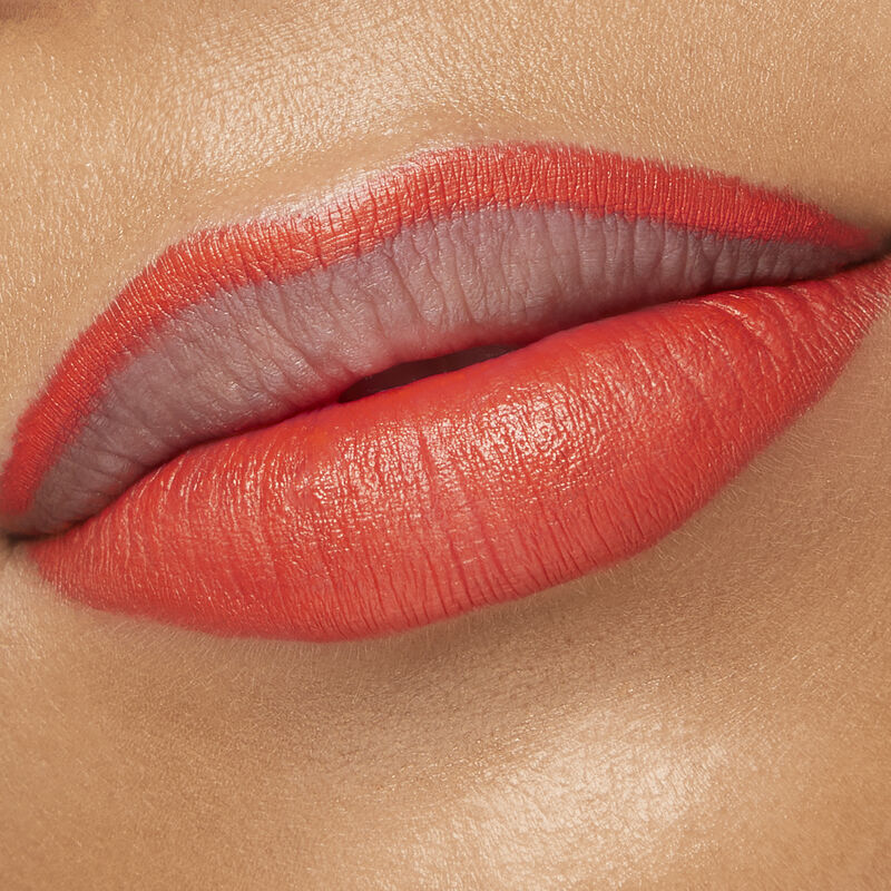 Close up of medium-skinned model with special-edition Mary Kay Waterproof Lip Liner in shade Tangerine outlining top lip and filling bottom lip