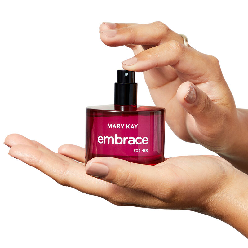 Bottle of Mary Kay Embrace for Her Eau de Toilette held in the hands of a fair-skinned woman with her pointer finger resting on the spray button