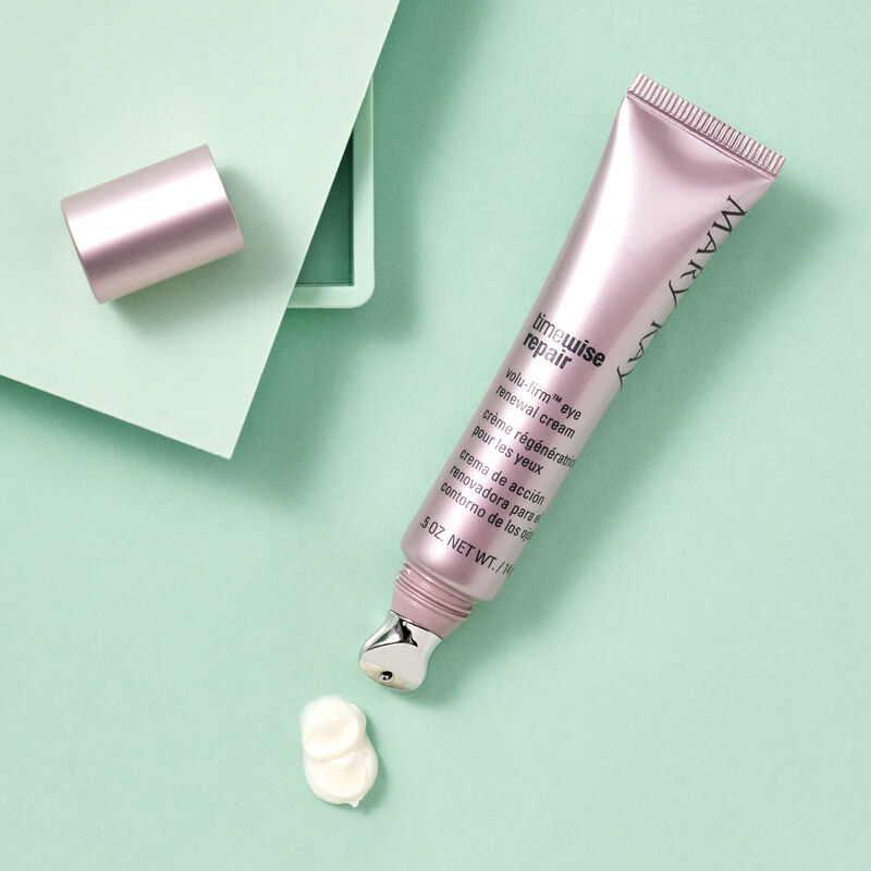 An open  tube of TimeWise Repair Volu-Firm Eye Renewal Cream from Mary Kay along with a product rub against a green background.