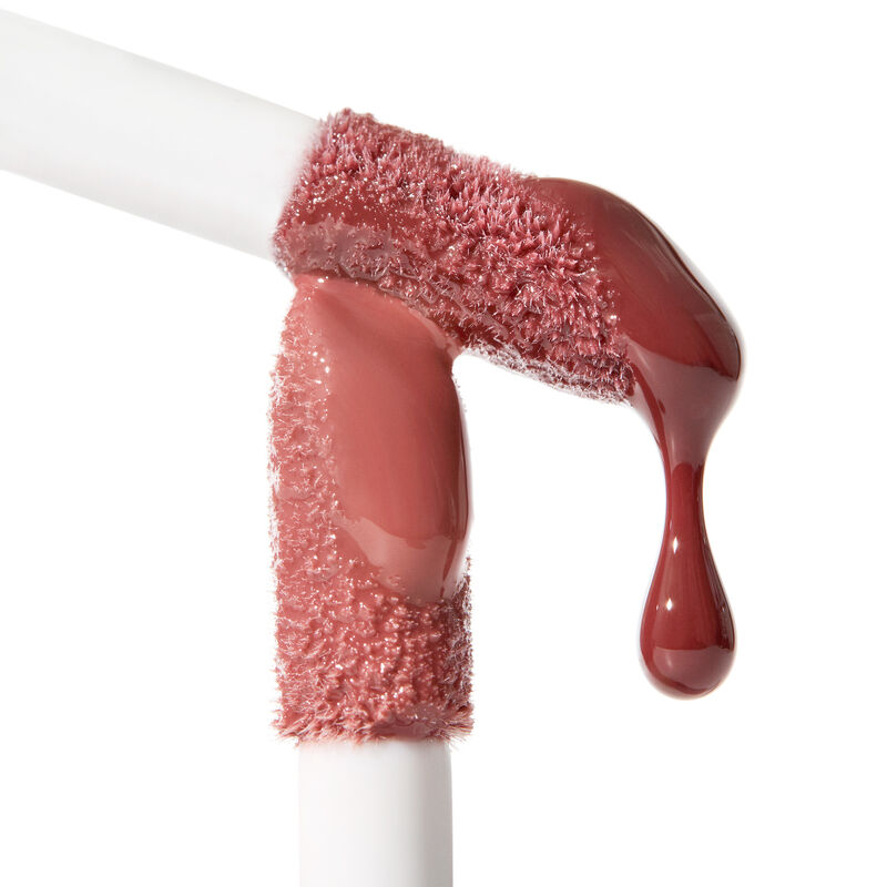 Thick doe foot applicators of Mary Kay Tinted Lip Oil in Blush with a shiny droplet of Mary Kay Tinted Lip Oil in Berry on applicator on white backgro