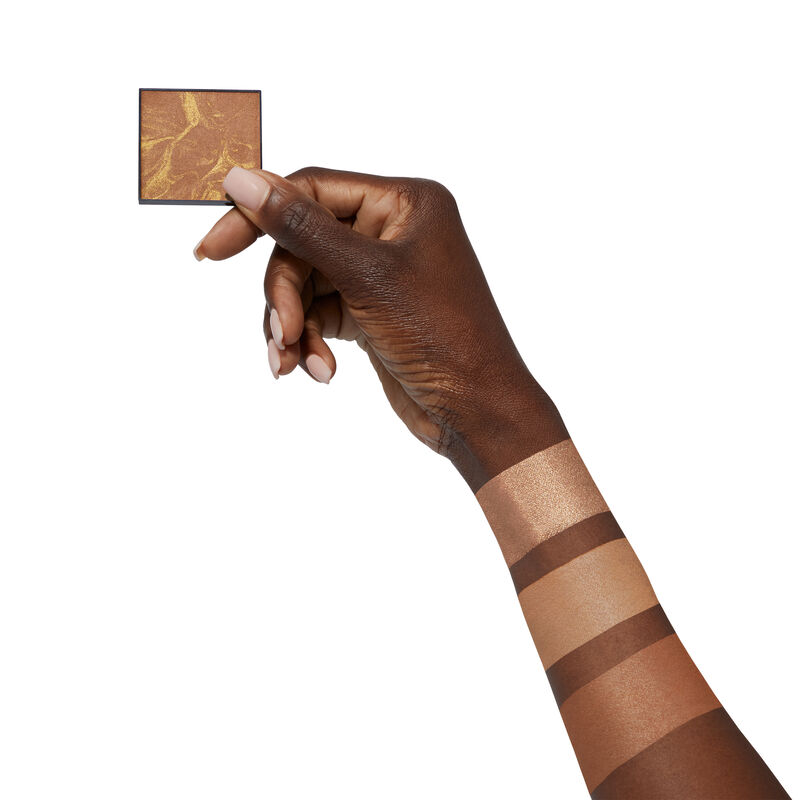 Medium-skinned hand holding limited-edition Mary Kay Illuminating Bronzer