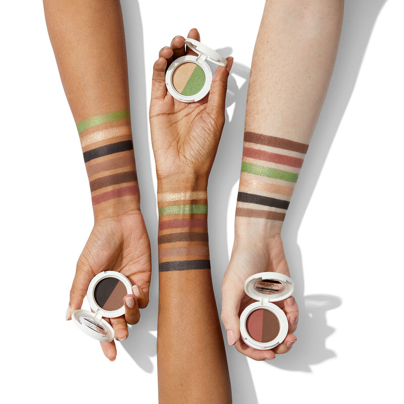 Diverse arms with swatches of all shades of special-edition Mary Kay At Play Eye Shadow Duos holding open compacts image number null