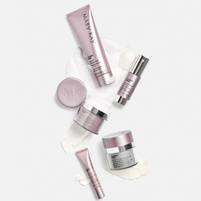The Mary Kay TimeWise Repair Volu-Firm Set against a gray background with product smears behind each product.