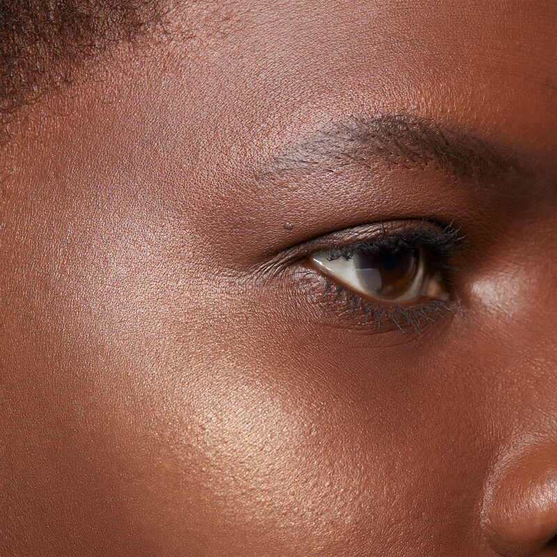 Close up of deep-skinned model with black hair and brown eyes wearing limited-edition Mary Kay Illuminating Bronzer