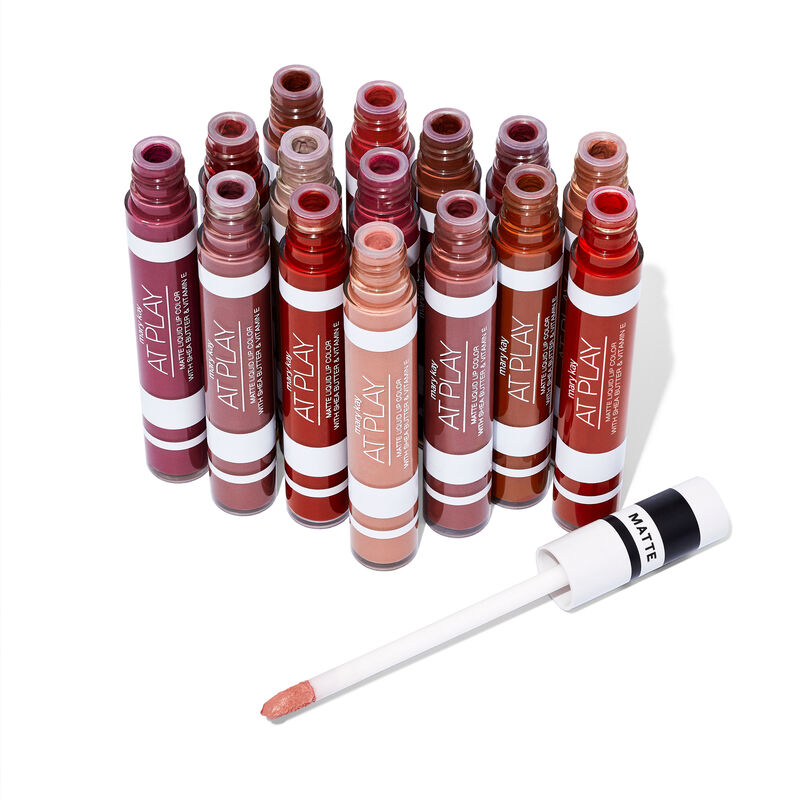 Tubes of Mary Kay At Play Matte Liquid Lip Color in all shades against plain background with an accompanying applicator