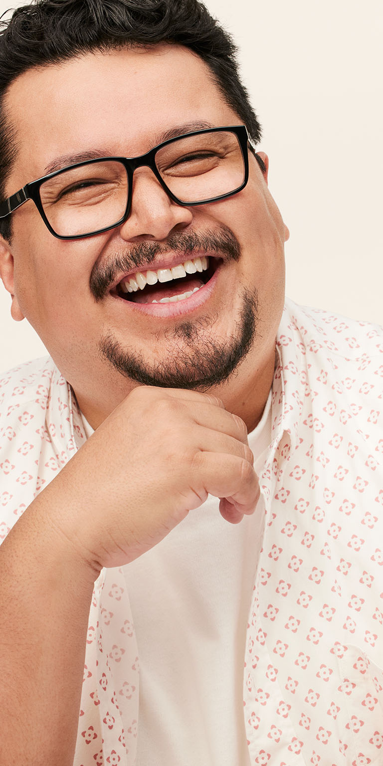 Modelo masculino sonriendo con la mano apoyada en el ment&oacute;n