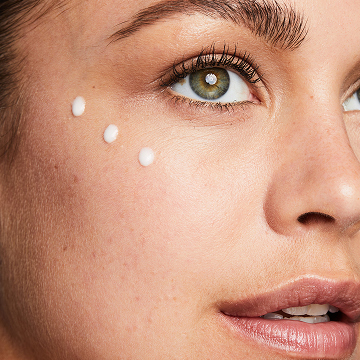 Mujer con tres puntos de Loci&oacute;n Facial Regeneradora C+E TimeWise&reg; en la mejilla.