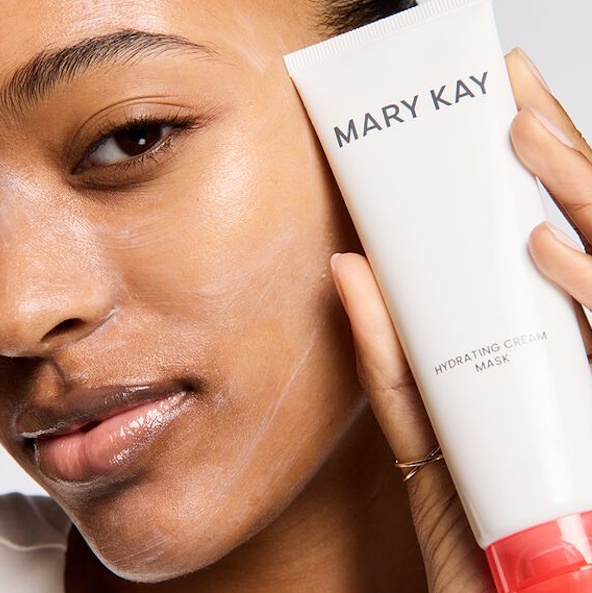 Modelo con aplicaci&oacute;n fina de mascarilla hidratante sosteniendo el tubo de mascarilla cerca del rostro.