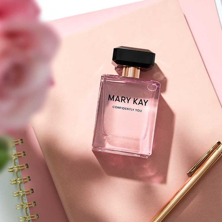 Frasco de Confidently You Eau de Parfum recostado sobre una libreta rosa