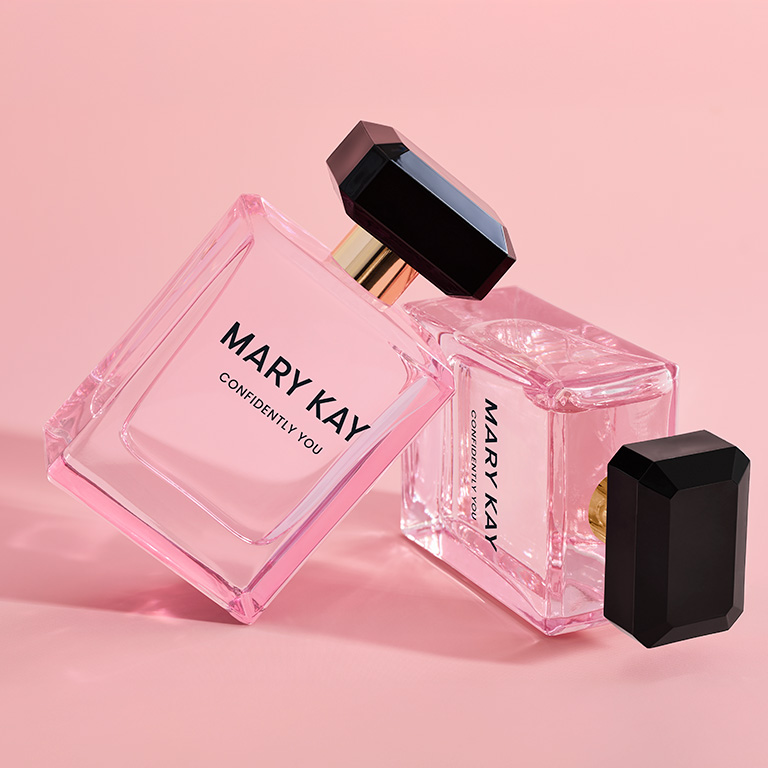 Dos frascos de Mary Kay Confidently You Eau de Parfum apilados uno sobre otro sobre un fondo rosa.