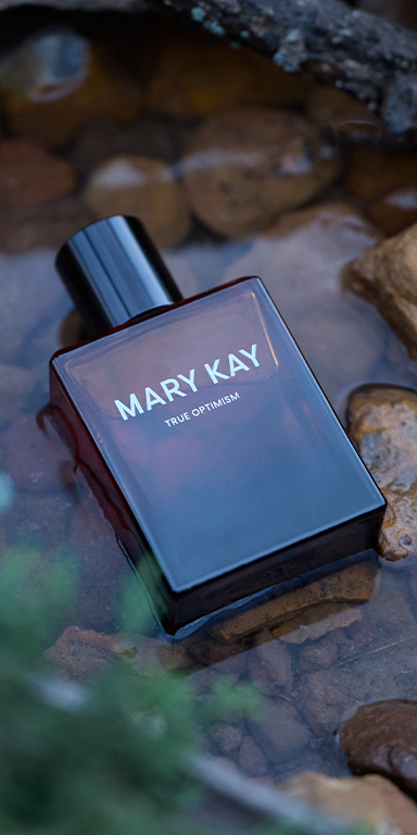 Frasco de Mary Kay True Optimism&reg; Eau de Parfum de 50 ml colocado sobre piedras junto al agua.