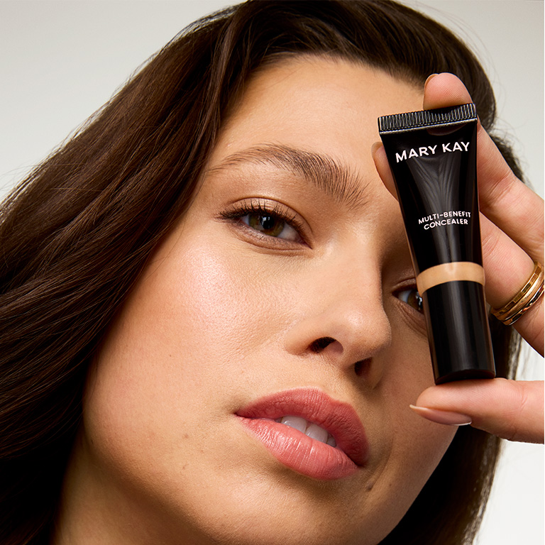 Modelo sosteniendo el Corrector para Ojos Multi‑Beneficios Mary Kay&reg; cerca del rostro